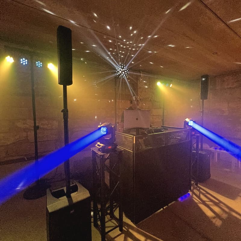 Cabina de DJ amb caps mòbils i feixos blaus sota una volta de pedra en una finca de Mallorca