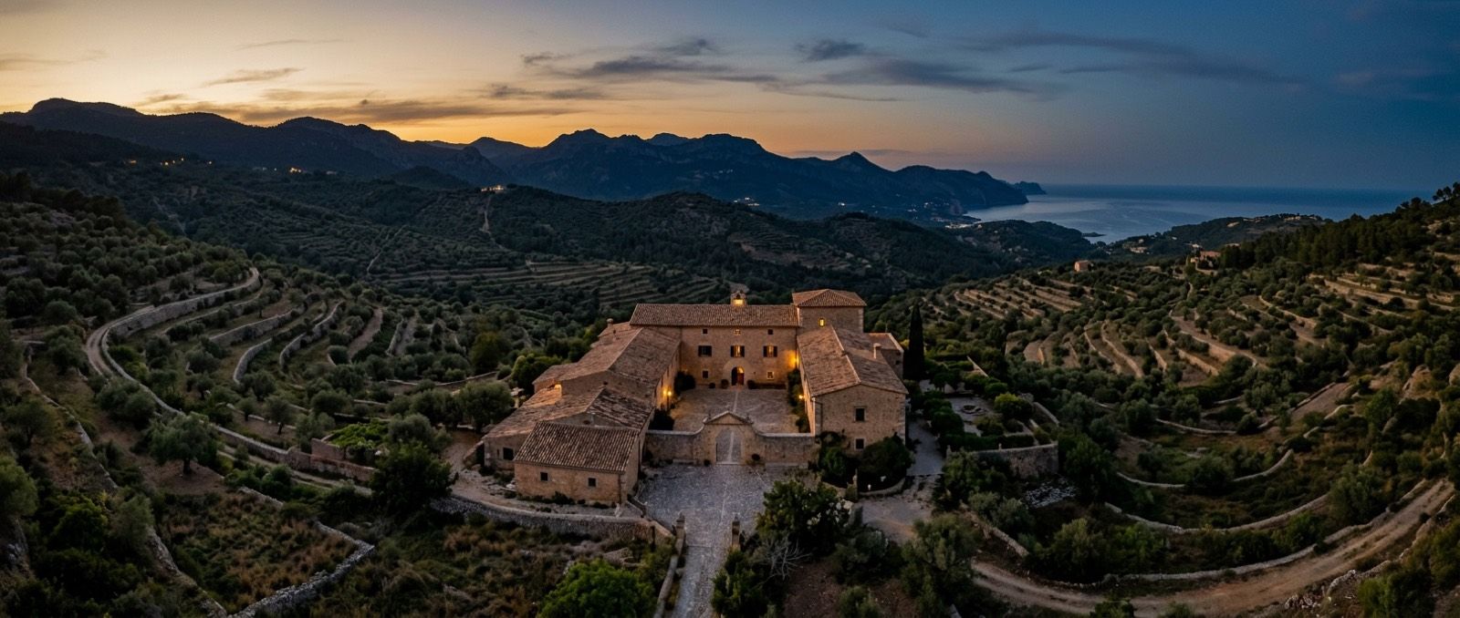 Terrace of a Mallorcan finca set up for an event at sunset, tables laid and mountain views behind